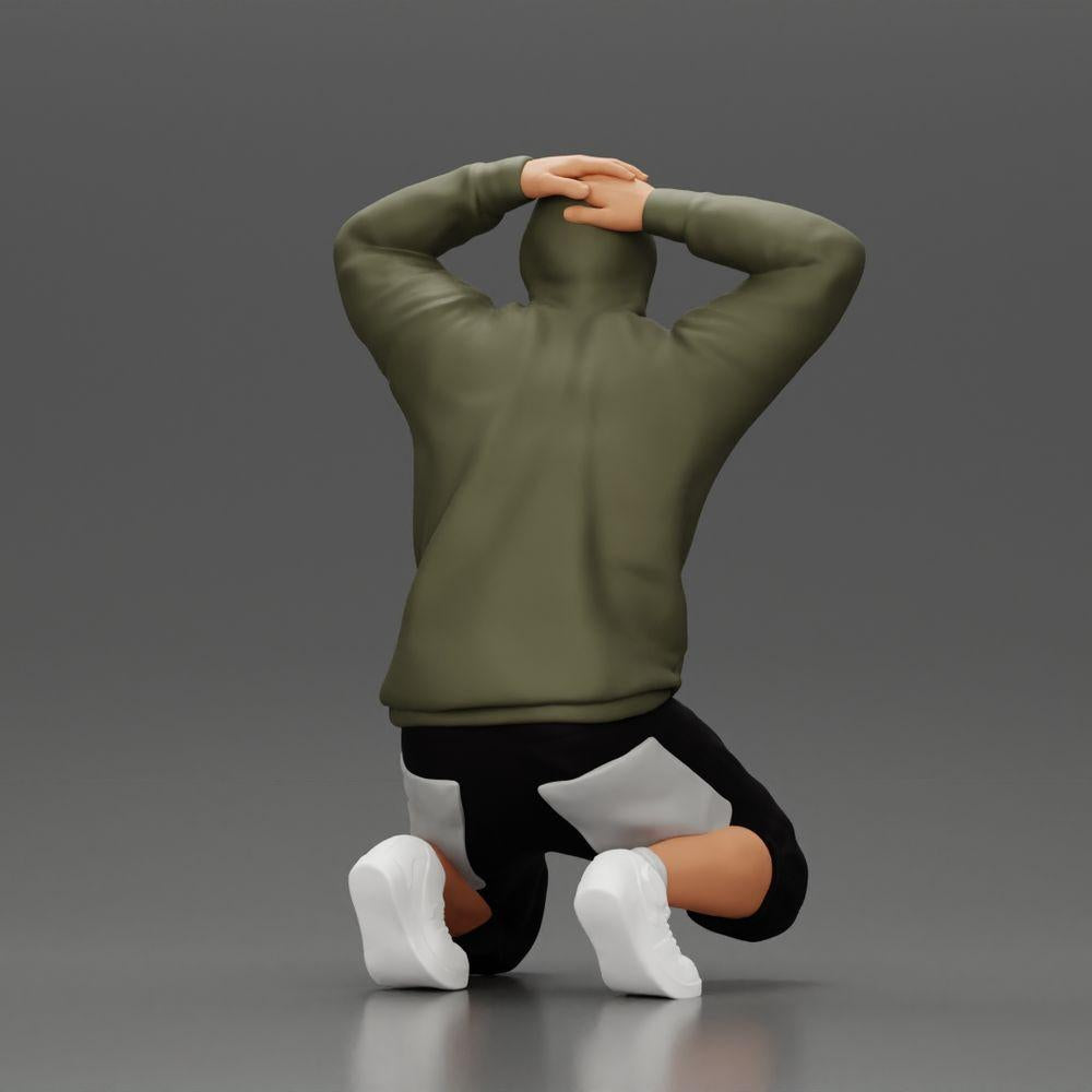 Modello diorama fotografia prodotto 2: Uomo inginocchiato con felpa con cappuccio, mani dietro la testa - Miniatura diorama (Rif. n. A70)